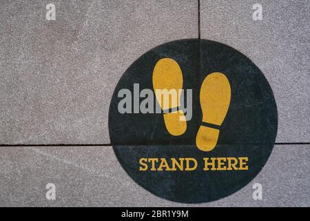 Tenez-vous debout ici, panneau ou symbole de pied sur le sol, style de vue de dessus Banque D'Images