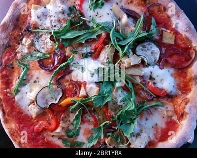 Pizza cuite au feu de bois de style méditerranéen recouverte de roquette fraîche Banque D'Images