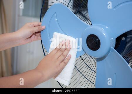 Gros plan de la femme nettoyant les mains de la pale de ventilateur électrique sale avec un chiffon blanc Banque D'Images