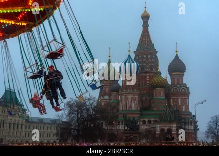 Vue sur le carrousel et la cathédrale Saint-Basile sur la place Rouge, photo prise par une journée de brouillard. Les enfants s'amusent sur le carrousel. Kremlin. Moscou. Banque D'Images