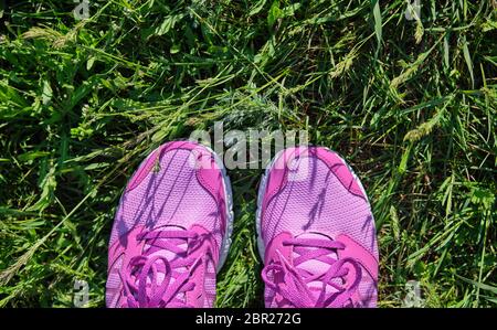 Les femmes rose chaussures avec lacets sur l'herbe verte fraîche, vue du dessus Banque D'Images
