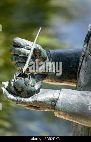 partie d'une statue de mains tenant le nénuphars et la brosse de peinture dépoussiérant le pollen pour la propagation Banque D'Images