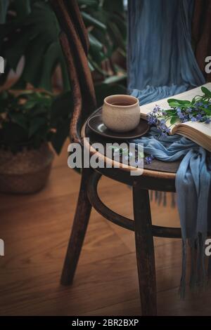 Une tasse de thé et un livre avec Forget Me nots sur une chaise Banque D'Images