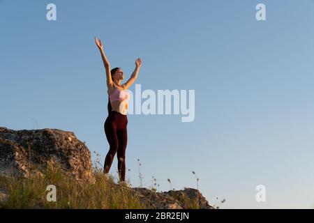 Portrait extérieur de la jeune femme heureuse avec les mains levées se détendant dans les montagnes lors d'une belle journée ensoleillée, paisible et harmonieuse humeur Banque D'Images