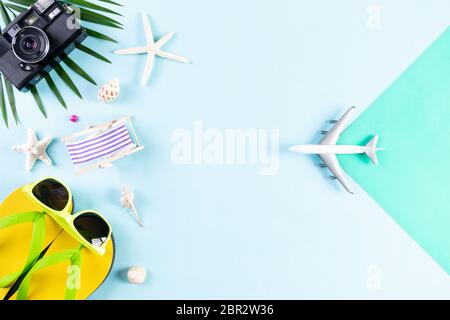 Accessoires de plage, appareil photo rétro film, avion, lunettes de soleil, chapeau de plage à fop et coquillages sur fond bleu pastel pour les vacances d'été an Banque D'Images