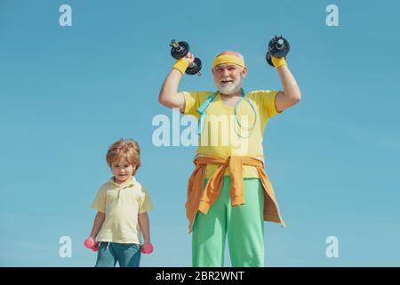 Grand-père aidant enfant à s'entraîner avec des haltères. Faire du sport est gratuit. Concept de vie saine et de sport. Bon petit garçon et grand-père de levage stupide Banque D'Images