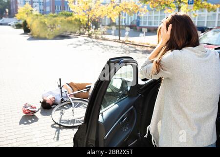 Choqué Woman Cyclist mâle inconscient allongé sur rue après accident près de voiture Banque D'Images