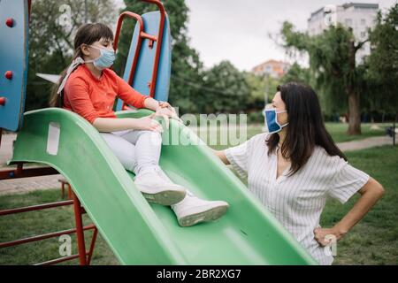 Mère et petite fille passant du temps de qualité à l'extérieur. Bonne fille portant un masque de protection se sentant confiante qu'elle peut utiliser la lame sous le cond sûr Banque D'Images