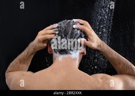 Vue arrière de l'homme tête de lavage avec un shampooing douche à Banque D'Images