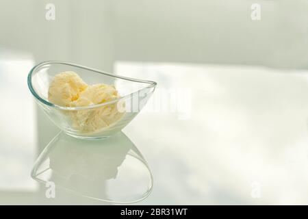 boule de glace vanille dans un bol en verre sur une table brillante Banque D'Images