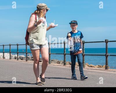 Sidmouth, East Devon, Royaume-Uni. 20 mai 2020. Météo au Royaume-Uni : une femme et un garçon se promènent le long de l'esplanade de Sidmouth en profitant du soleil brûlant avant le week-end des vacances en banque. Crédit : DWR/Alamy Live News Banque D'Images