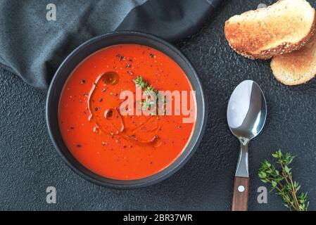 Bol de soupe aux tomates épicées garnies d'éclaboussure d'huile d'olive et poivre noir Banque D'Images