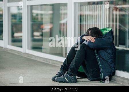 Petit garçon ou enfant assis seul sur le sol devant l'école après avoir subi un acte d'intimidation Banque D'Images