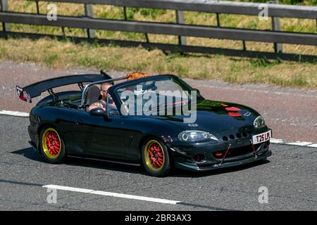 Mazda MX-5 1.8i 2013 noir avec mannequin assis sur le siège passager; personnalisé, rare style de vie, modifié, personnalisation, moteurs personnalisés inhabituels, modding, sur mesure. Circulation automobile véhicules en mouvement, conduite de véhicules sur les routes britanniques, moteurs, conduite sur l'autoroute M6 Banque D'Images