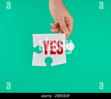 Big White puzzle dans la main sur un fond vert, l'inscription est oui Banque D'Images