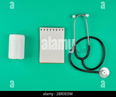 Ordinateur portable ouvert en ligne avec des draps blancs et stéthoscope sur fond vert. Banque D'Images