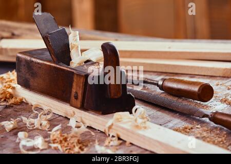 Avion en bois Vintage sur une planche de bois entourés de copeaux de lissage de la surface avec une râpe, fichier et du bois sur un établi Banque D'Images