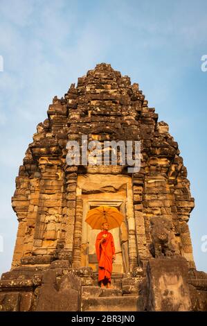 Un Monk se tient avec un parasol devant un temple à Roluos. Angkor, site du patrimoine mondial de l'UNESCO, province de Siem Reap, Cambodge, Asie du Sud-est Banque D'Images