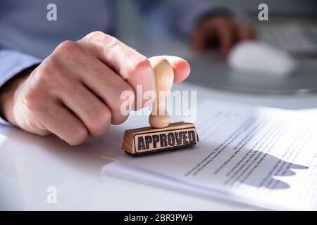 Close-up of a person's Hand Stamping avec timbre approuvé sur le document At Desk Banque D'Images