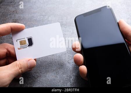 De l'homme près de la carte SIM du smartphone sur le fond en béton Banque D'Images