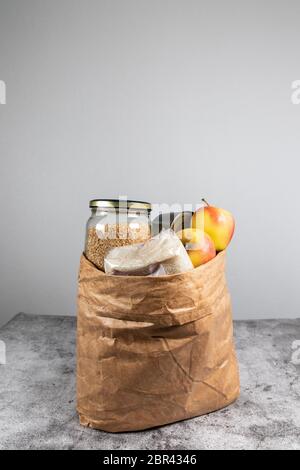 Sac de papier pour dons fournitures alimentaires pour personnes isolées sur fond gris avec espace pour les copies. Verticale Banque D'Images