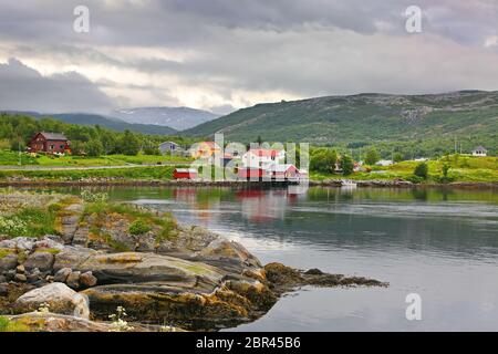 Magnifique paysage avec bord d'eau, village, église et montagnes en arrière-plan, Saltspraumen, municipalité de Bodo, comté de Nordland, Norvège. Banque D'Images
