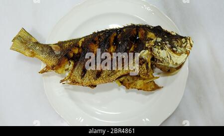 Un poisson fusilier entier, frit et servi sur une assiette. Vue de dessus. Banque D'Images