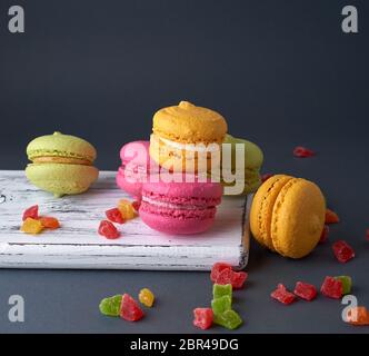 Des gâteaux multicolores de la farine d'amande macarons sur une planche de bois blanc, fond noir Banque D'Images