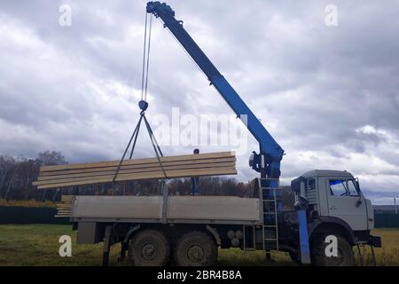 La grue sur fond de ciel décharge les planches sur le chantier de construction.2020 Banque D'Images