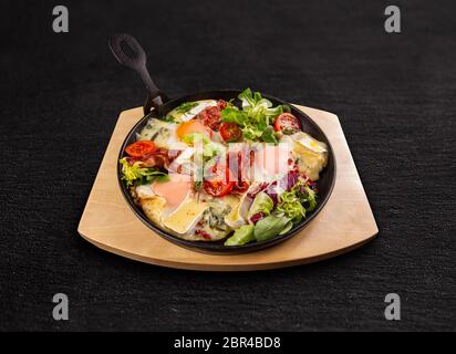 Les oeufs au plat avec du bacon frit croustillant, salade et tomates en fry pan Banque D'Images