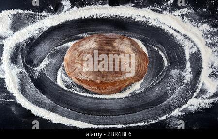 De pain frais et de la farine de blé blanche éparpillés sur un tableau noir, vue du dessus Banque D'Images