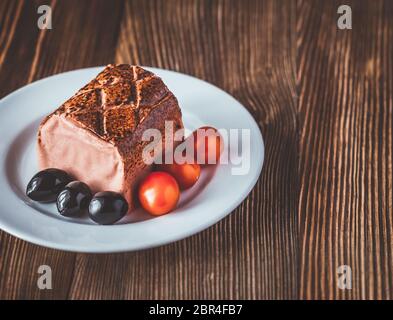 Le pâté de foie de poulet aux olives noires et tomates cerises sur la plaque blanche Banque D'Images