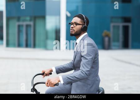 Homme d'affaires noir dans les écouteurs à vélo Banque D'Images
