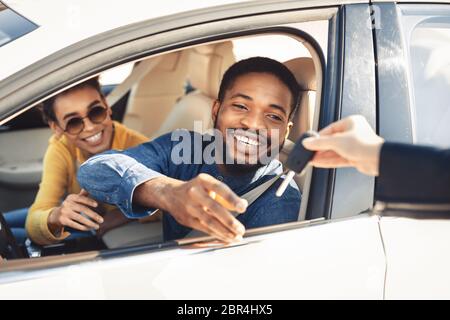 Heureux conjoints prenant la clé pour l'essai routier assis dans une voiture Banque D'Images