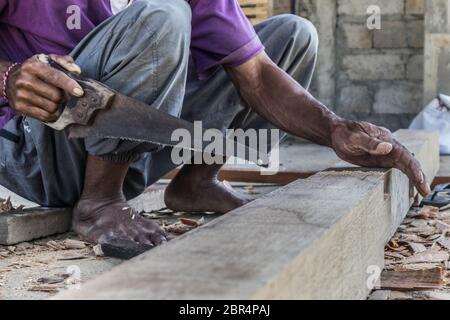 Close up d'avertir les mains de menuisier travaillant avec des outils manuels traditionnels de menuiserie de pays en développement. Forte de main-d'oeuvre des travaux manuels. Banque D'Images