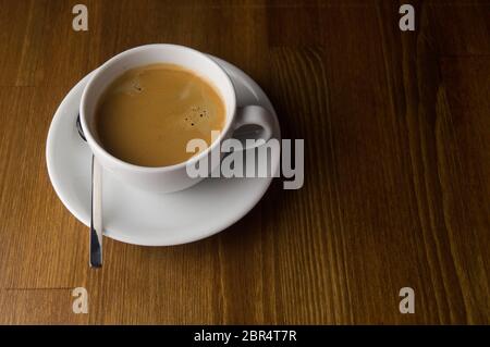 Une tasse de café et la cuillère placée sur une table marron Banque D'Images