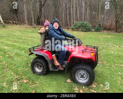 Fille Litle monte sur un quad avec son père, ils sont tous deux à la recherche de l'appareil photo. Banque D'Images