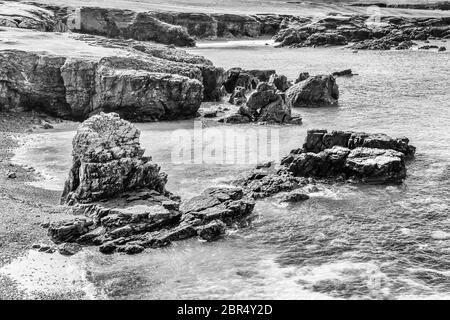 Falaises et rochers accidentés sur la côte ouest de l'Écosse en noir et blanc Banque D'Images
