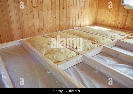 Pose de la couche d'isolation thermique sous le plancher avec de la laine minérale dans la chambre de la maison de campagne. Réchauffement d'un sol étape par étape. Banque D'Images