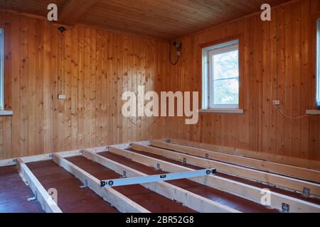 Installation de poutres longitudinales pour le réchauffement d'un plancher dans la maison de bois de campagne. Réchauffement d'un sol étape par étape. Banque D'Images