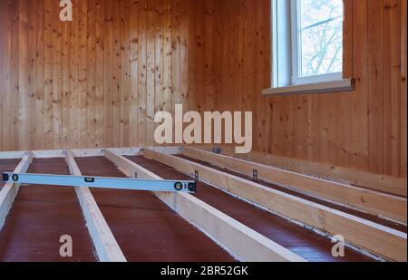 Installation de poutres longitudinales pour le réchauffement d'un plancher dans la maison de bois de campagne. Réchauffement d'un sol étape par étape. Banque D'Images