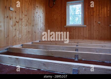 Installation de poutres longitudinales pour le réchauffement d'un plancher dans la maison de bois de campagne. Réchauffement d'un sol étape par étape. Banque D'Images