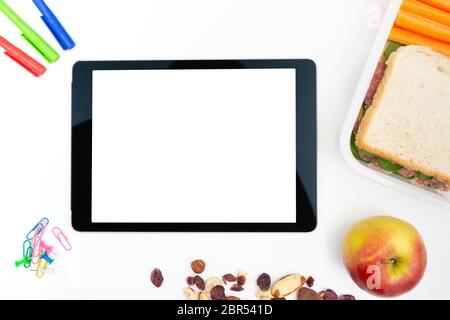 Manger un sandwich sain en boîte à lunch au travail avec tablette sur tableau blanc Banque D'Images
