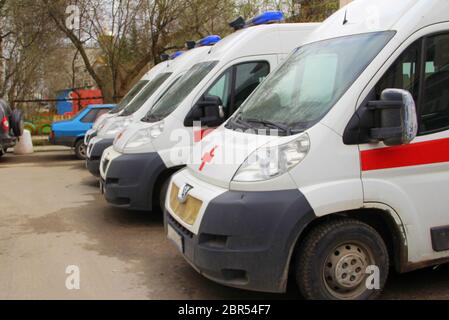 Ambulance blanche avec une bande rouge et des feux bleus clignotants sur une rue de la ville en Russie. Banque D'Images