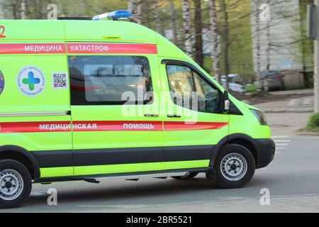 Ambulance blanche avec une bande rouge et des feux bleus clignotants sur une rue de la ville en Russie. Banque D'Images