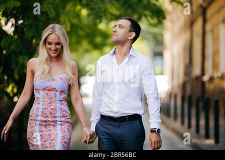 en descendant la rue ensemble. Joyeux jeune homme et femme souriante marchant dans les rues de la vieille ville, Banque D'Images