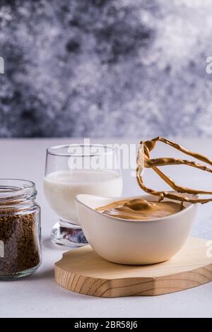 Cuisson du café Dalgona avec de la mousse fouettée . La crème de café Dalgona faite de café instantané, sucre et lait est dans une tasse et un fouet d'un mélangeur. Banque D'Images