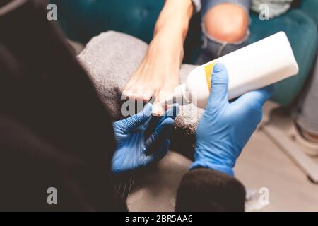 le pédicuriste fait une procédure de beauté pour le client. Bouteille d'huile pour cuticule Banque D'Images