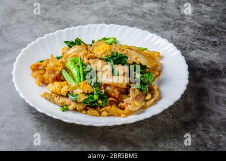 Sauté de nouilles de farine de riz frais avec des tranches de porc, d'oeufs et de chou frisé. Sauté de nouilles rapide. Banque D'Images