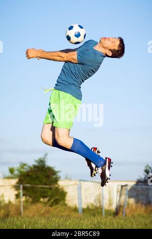 Moment de sport de saut joueur de football avec ballon de football dans l'air, action sur terrain de football.